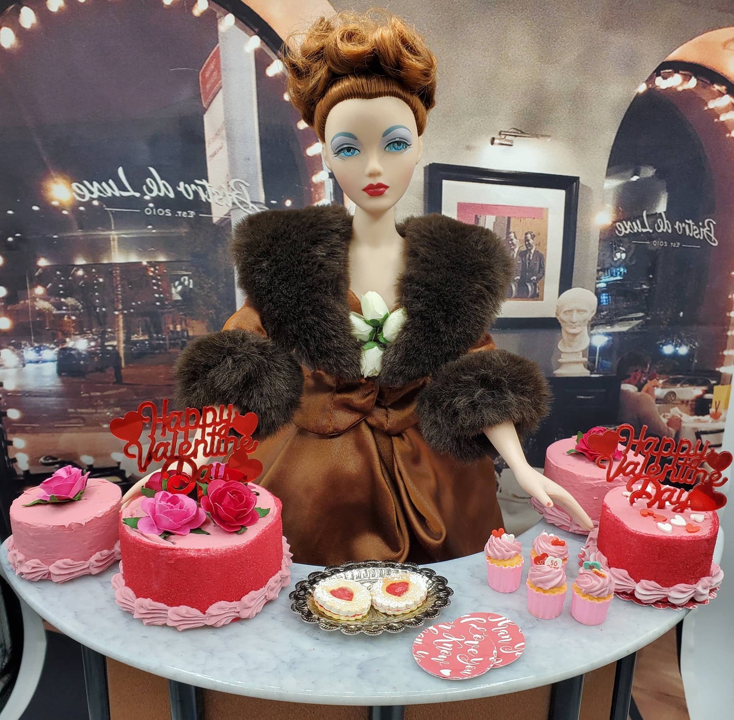 Chef Gina’s mini Linzer cookies dolls display with two pink cakes and assorted pink cupcakes on table