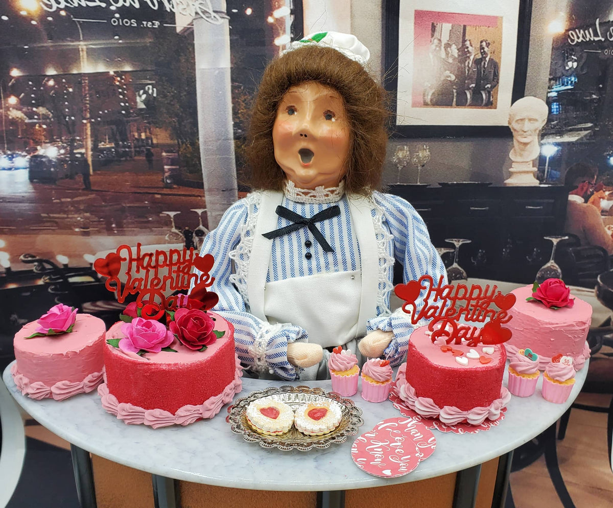 Chef Gina's mini Linzer cookies dolls displayed with pink cakes and cupcakes on a table
