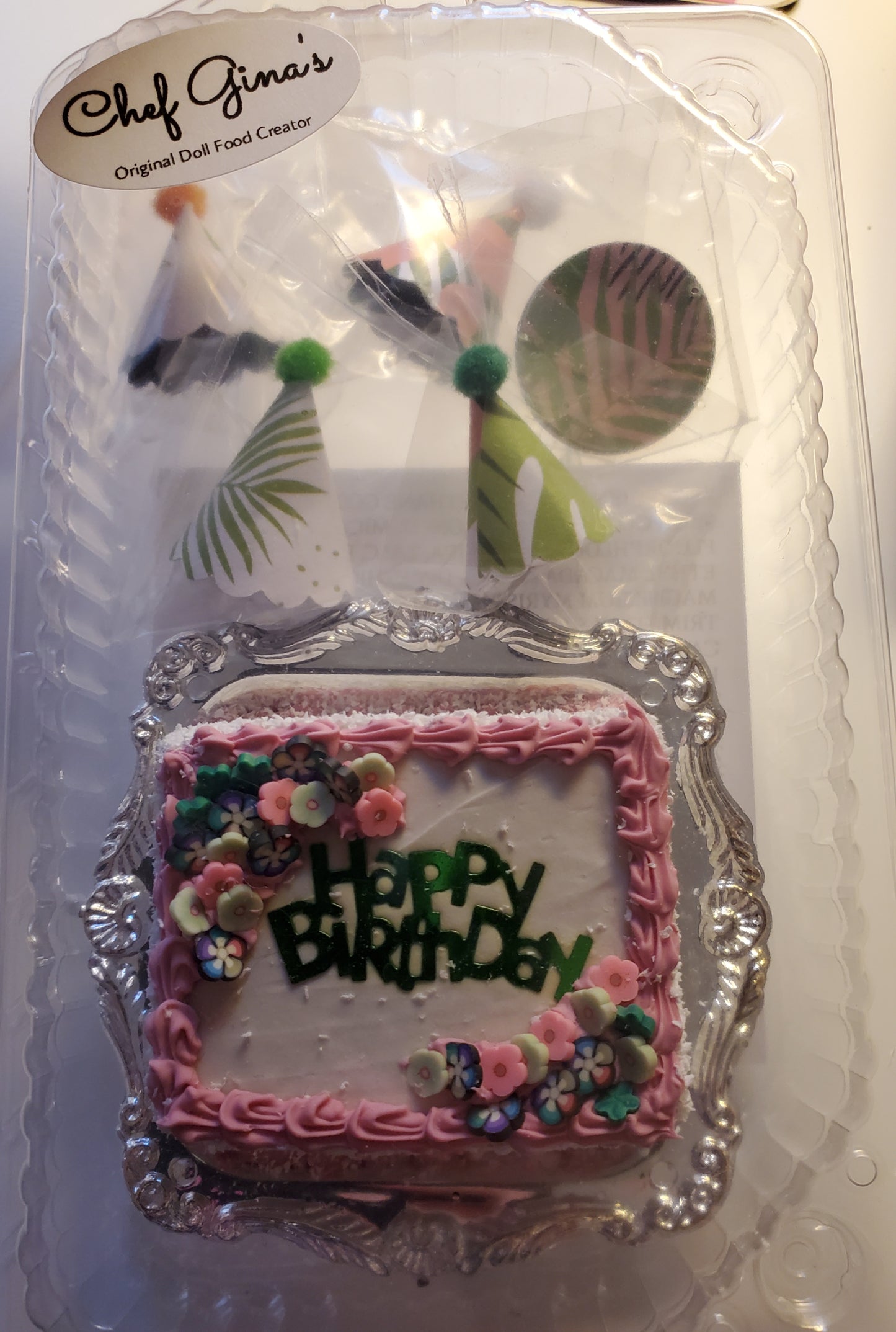 Chef Gina's miniature birthday party set cake with pink frosting and floral decorations in clear packaging