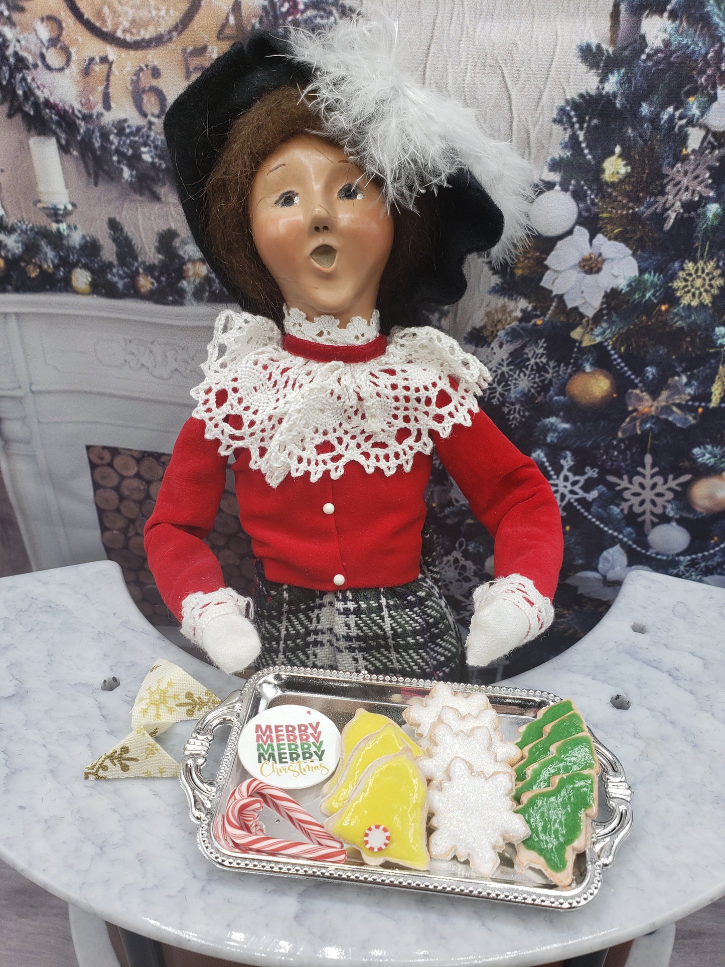 Miniature Christmas cookies for dolls displayed on a silver tray held by a vintage-style doll wearing a red blouse and lace collar