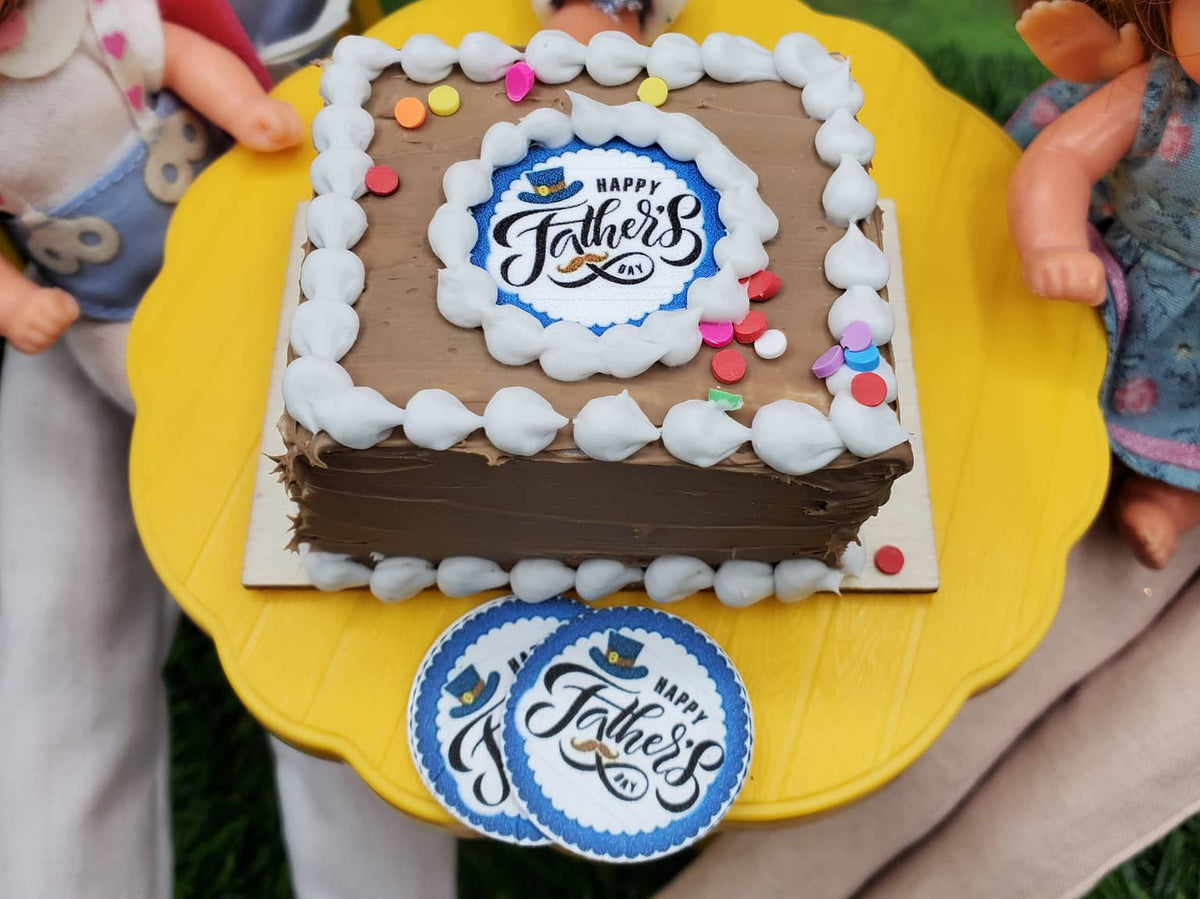 Miniature Father's Day cake with chocolate frosting and festive decorations on a yellow cake stand