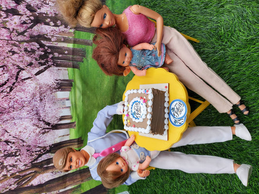 Miniature Father's Day cake on a table with dolls celebrating outdoors in a park setting