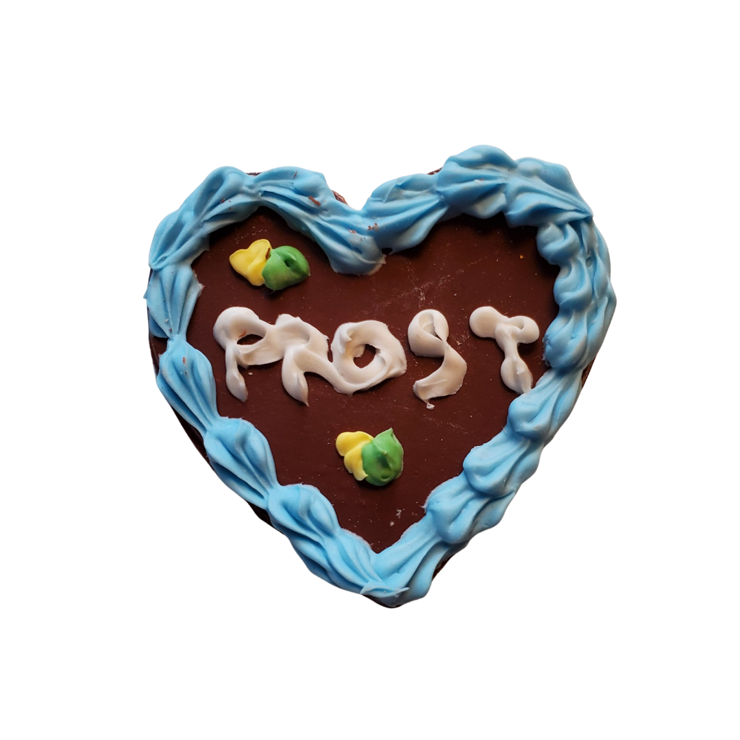 Miniature gingerbread heart cookie with blue icing border and frosted text saying Prost by Chef Gina's Oktoberfest