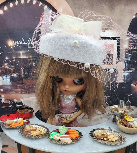 Chef Gina's miniature Mardi Gras torte dessert displayed on a table with a doll wearing a white hat with netting