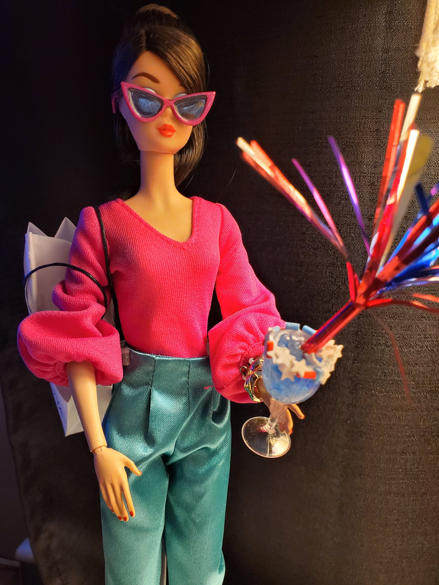 Barbie doll in pink sweater and teal pants holding miniature sparkler drinks for fun playtime accessories