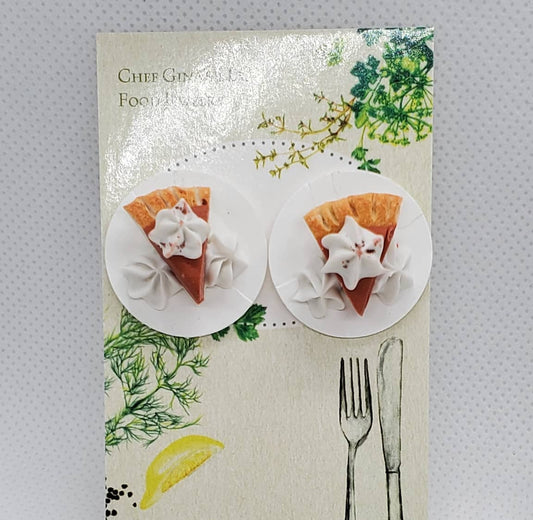A pair of round stud earrings mounted on a decorative display card. The earrings are white with a small orange-pink star-shaped center and a tiny silver star accent.