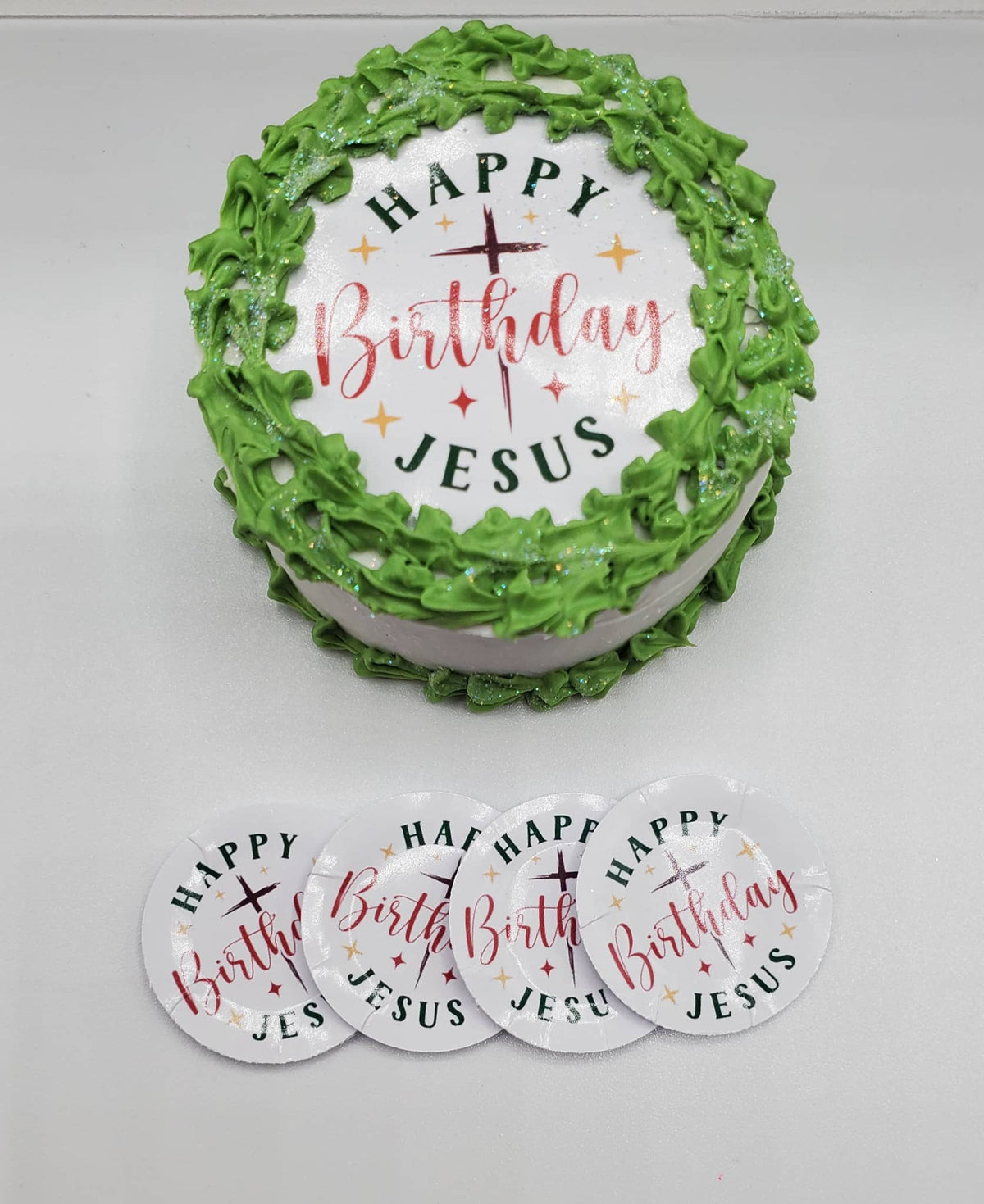 Birthday cake with 'Happy Birthday Jesus' text and green icing, accompanied by smaller decorative plates.