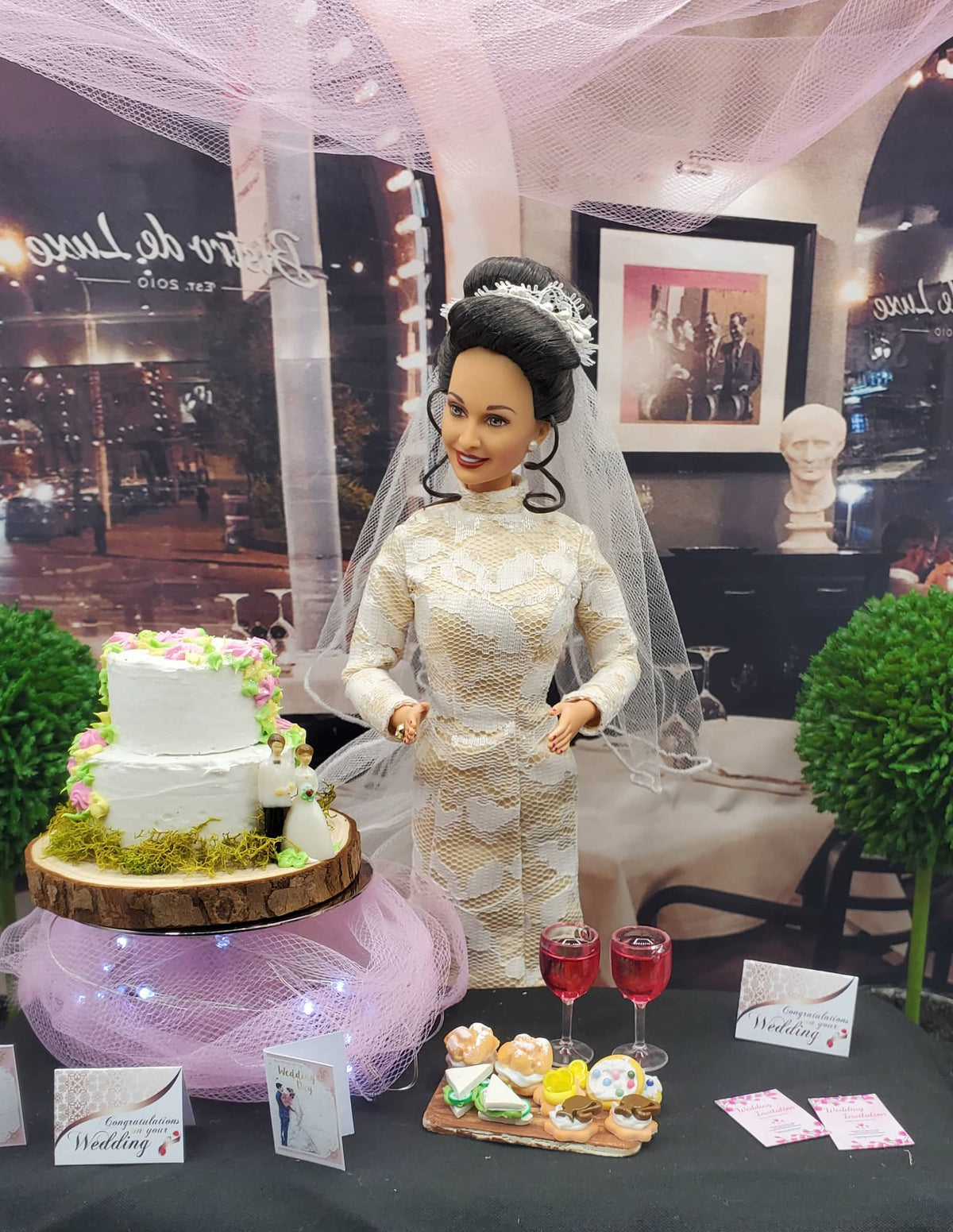 Barbie doll in a wedding dress with a cake and flowers on a table.