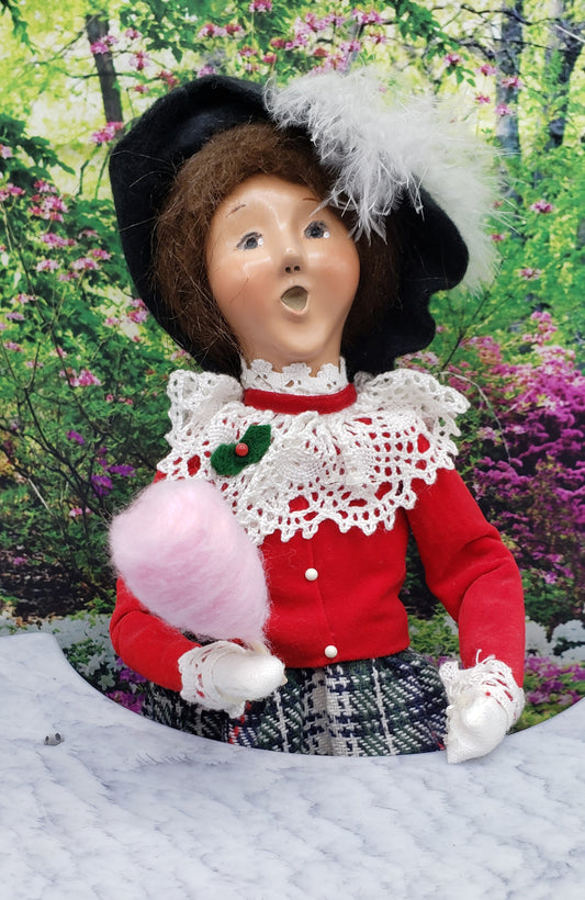 Vintage doll holding 1:6 scale cotton candy for dolls in a garden with floral background