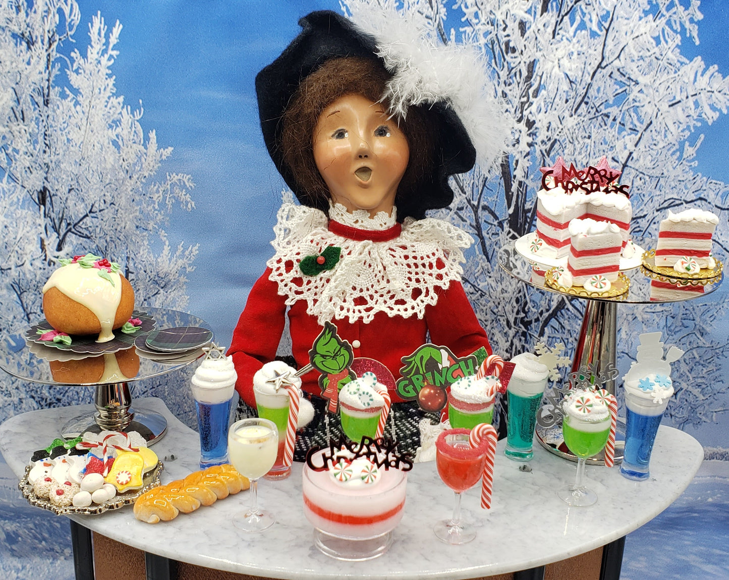 Miniature candy cane drink and holiday desserts displayed with vintage Christmas doll decoration