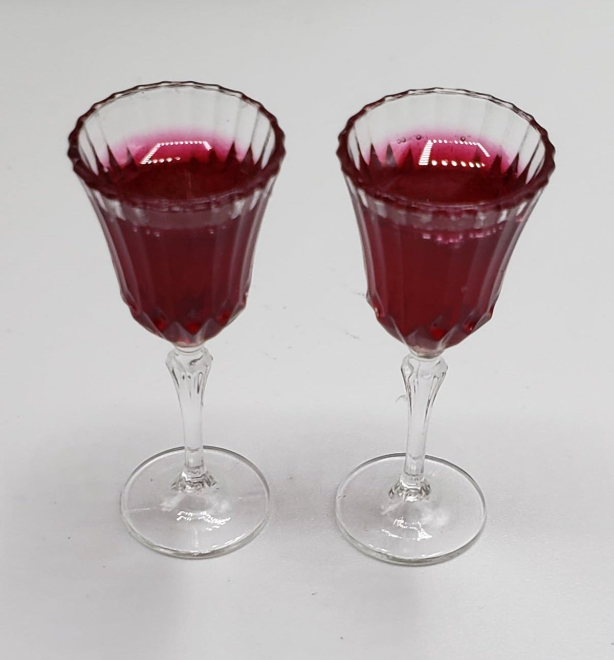 Two miniature crystal wine goblet filled with red wine on a white background by Chef Ginas Mini Food