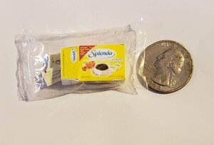Miniature Splenda packets next to a quarter for size comparison, ideal for sweetening beverages