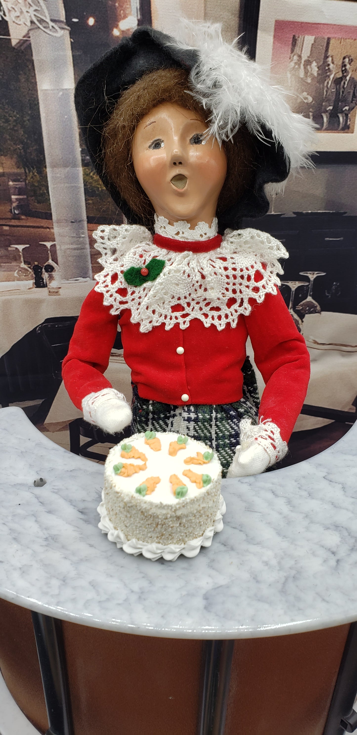 Realistic doll food carrot cake displayed on a table with a vintage doll in a festive outfit