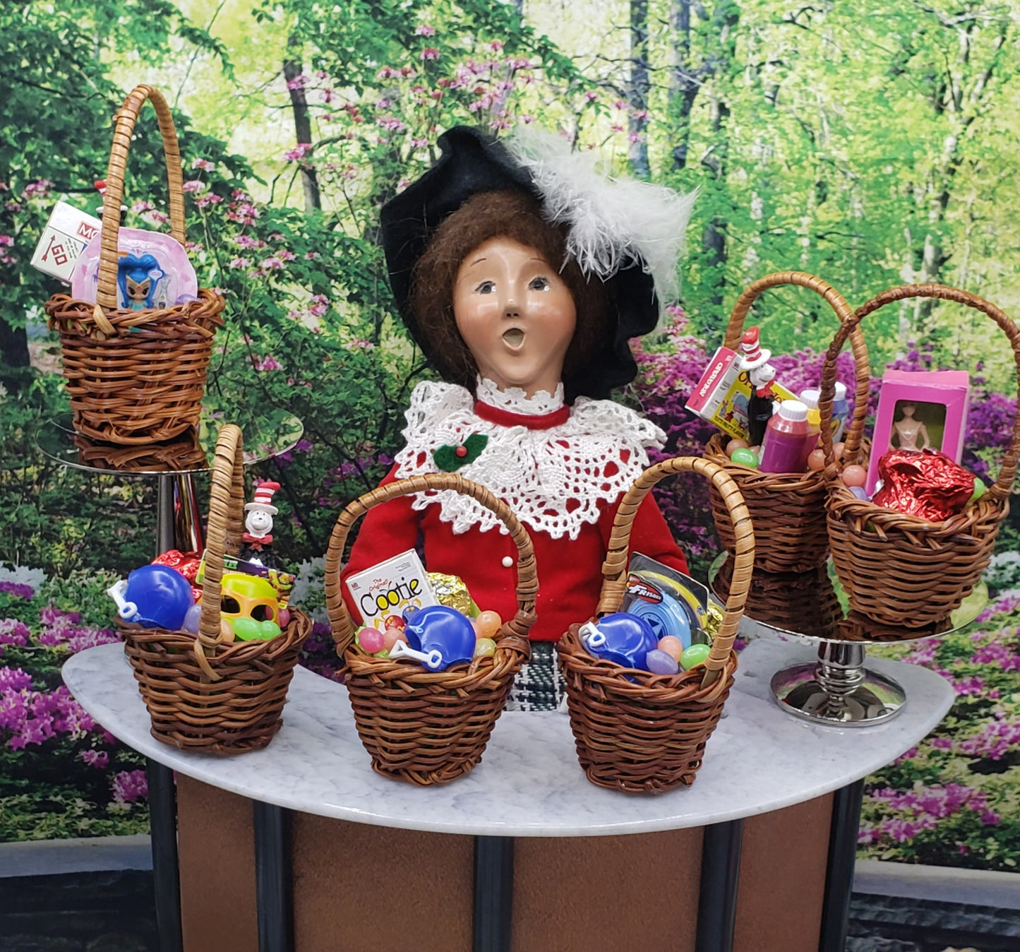 1:6 scale Easter basket accessories displayed in mini wicker baskets around a doll with a feathered hat