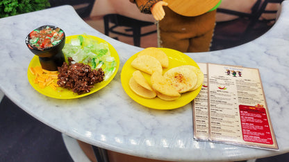 Two yellow plates with food on a marble table, next to a menu.