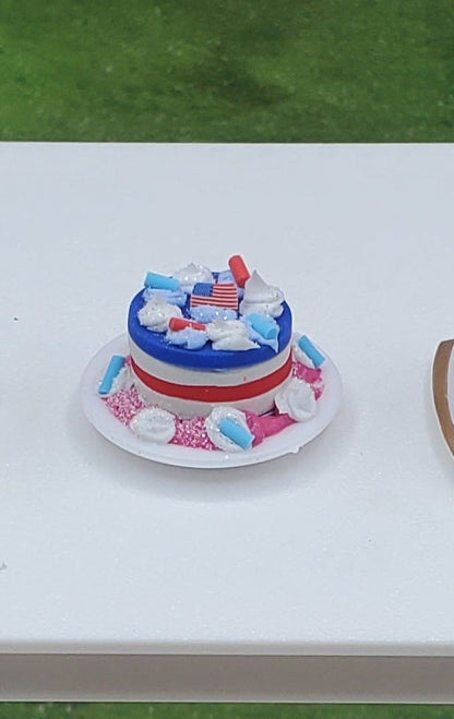 Five small decorated cakes on a table outdoors with grass and trees in the background