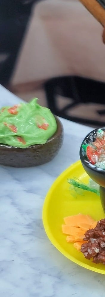 Miniature plates with food items on a table, with a person in a costume in the background.