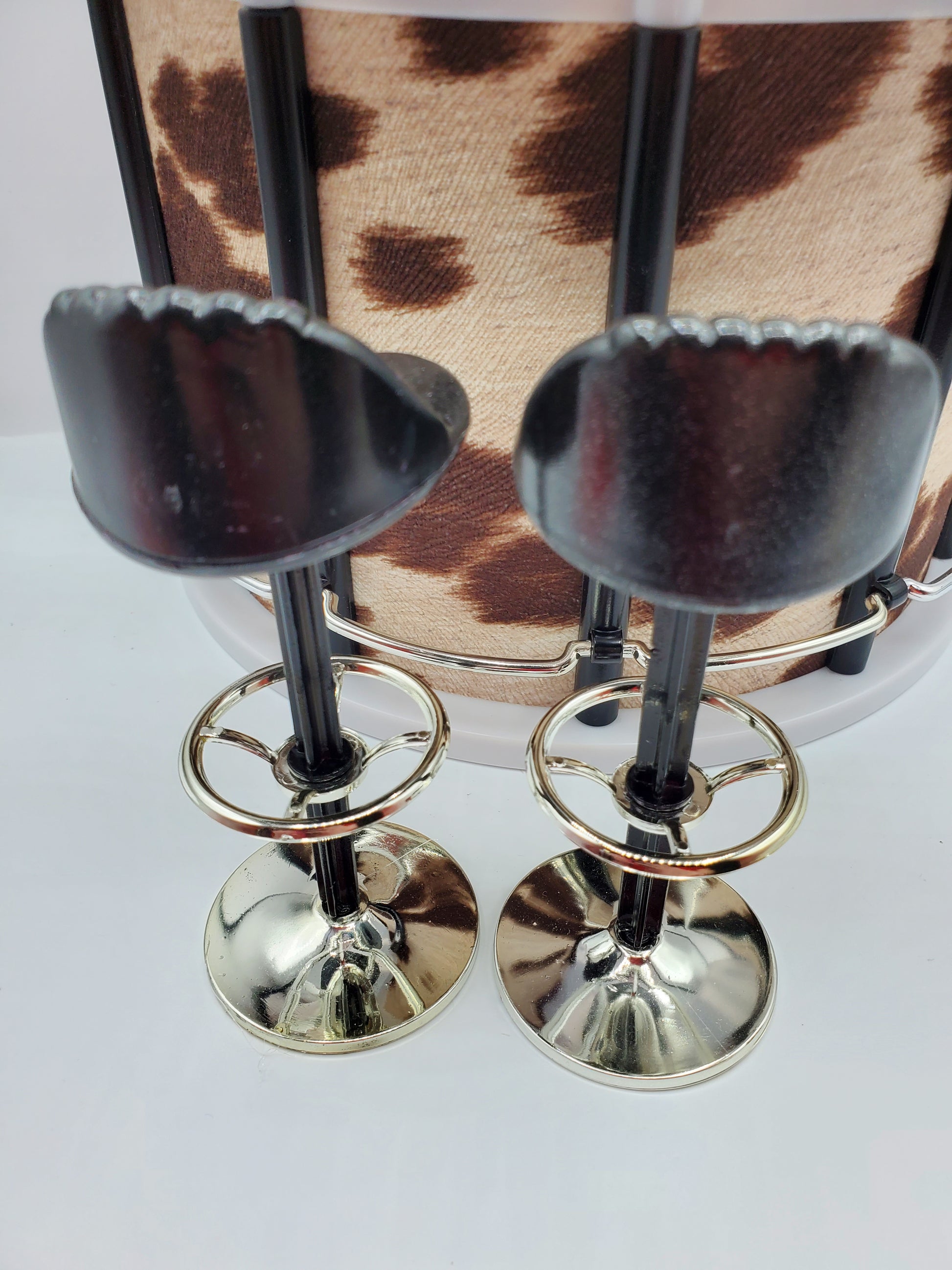 Country western bar set for dolls featuring two black and silver miniature bar stools with cowhide backdrop
