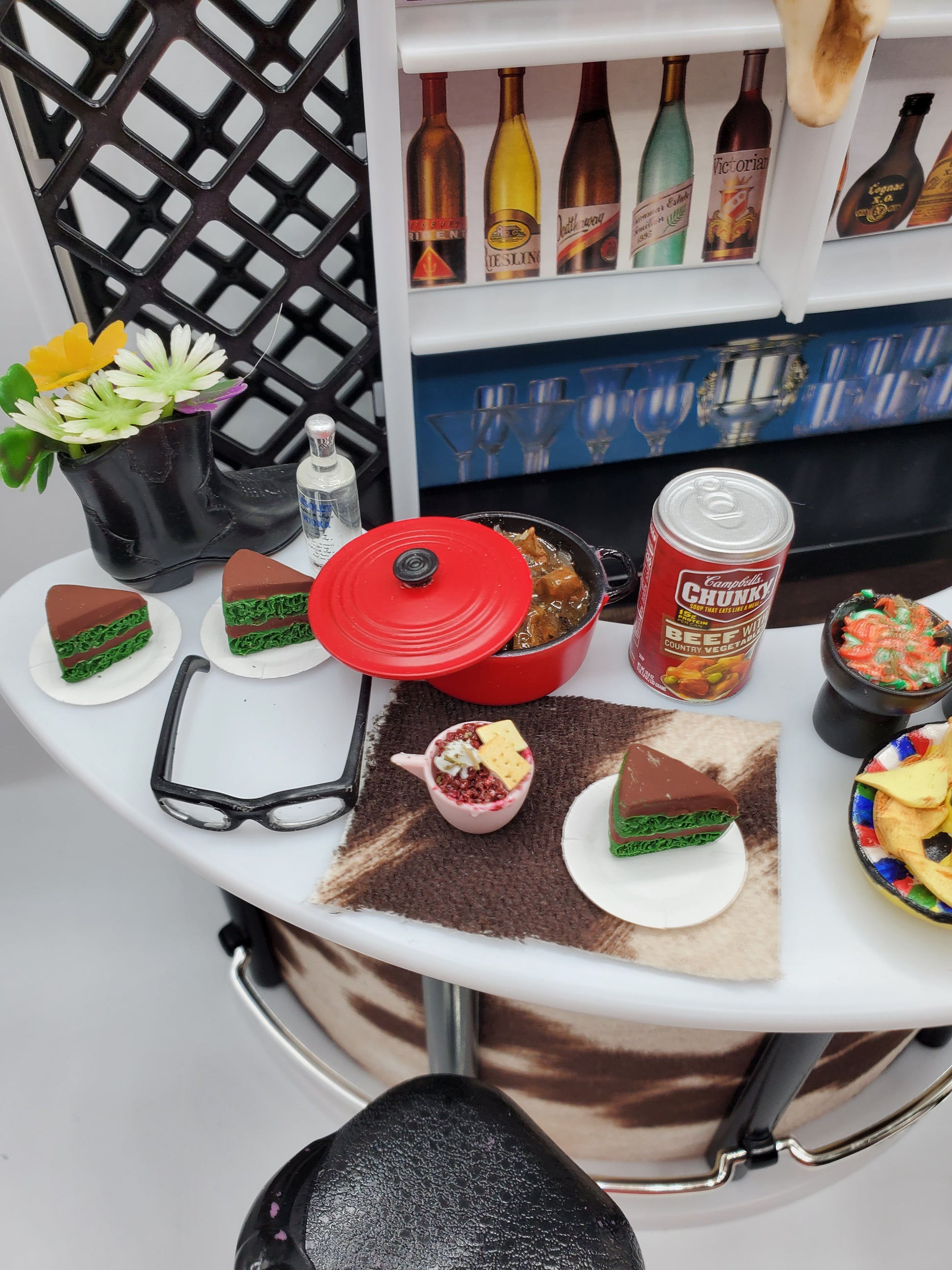 Country western bar set for dolls featuring miniature drinks, food, and cowboy boots on a bar counter