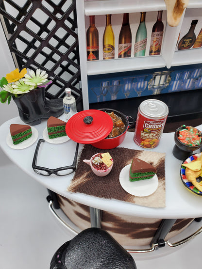 Country western bar set for dolls featuring miniature drinks, food, and cowboy boots on a bar counter