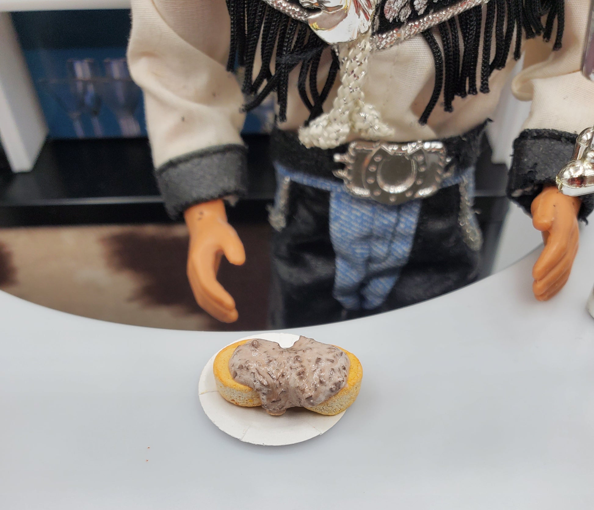Chef Gina's miniature biscuits and gravy for dolls on a small plate in front of a doll dressed in western attire