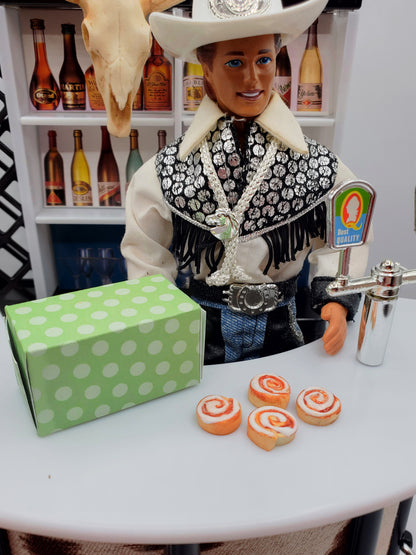 Miniature Texas cinnamon rolls for Fashion dolls displayed on a table with a cowboy doll and green polka dot box