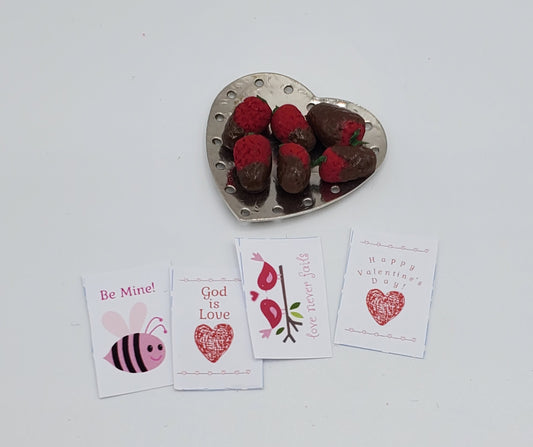 Heart-shaped dish with chocolate-dipped strawberries and Valentine's Day cards on a white background