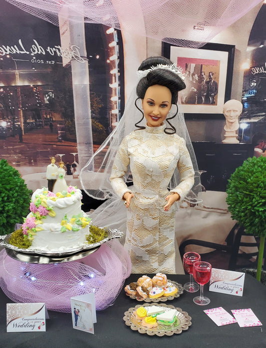 Barbie doll in a wedding dress with a cake and other decorations on a table.