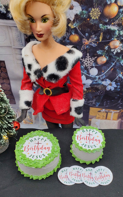 Barbie doll in a red outfit with fur trim standing next to two birthday cakes and 'Happy Birthday Jesus' signs.
