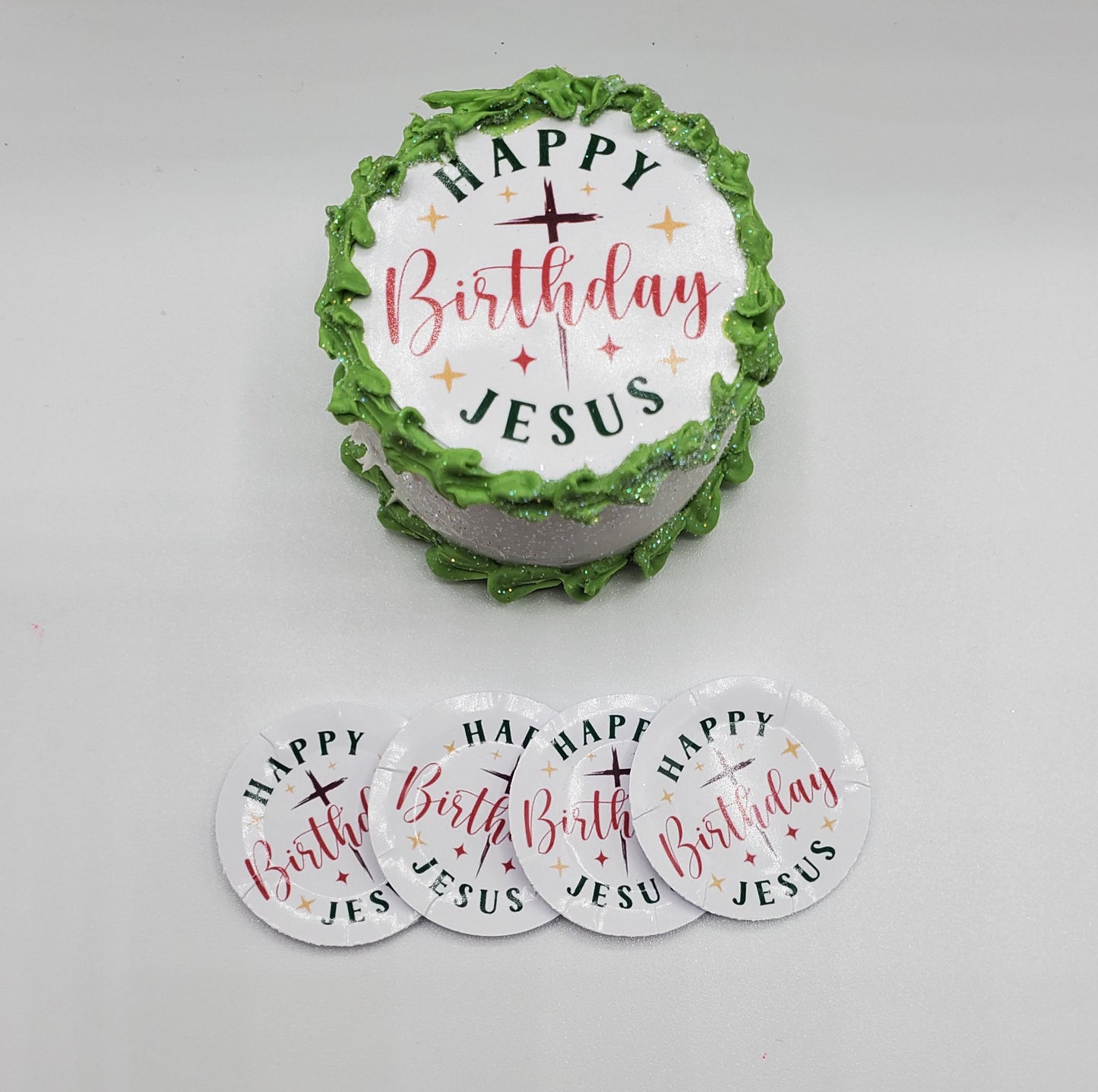Decorative cake with 'Happy Birthday Jesus' text and matching coasters on a white background