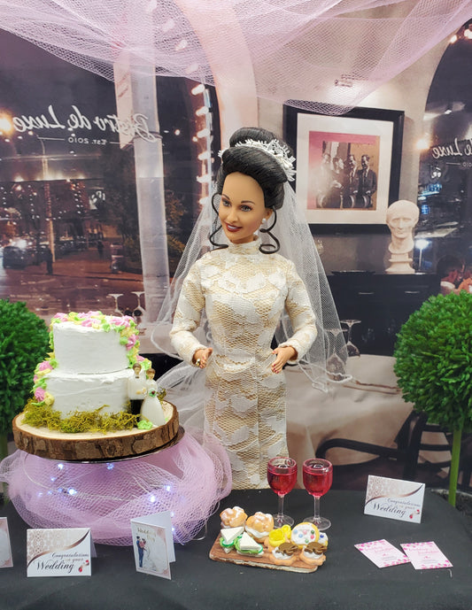 Barbie doll in a wedding dress with a cake and flowers on a table.