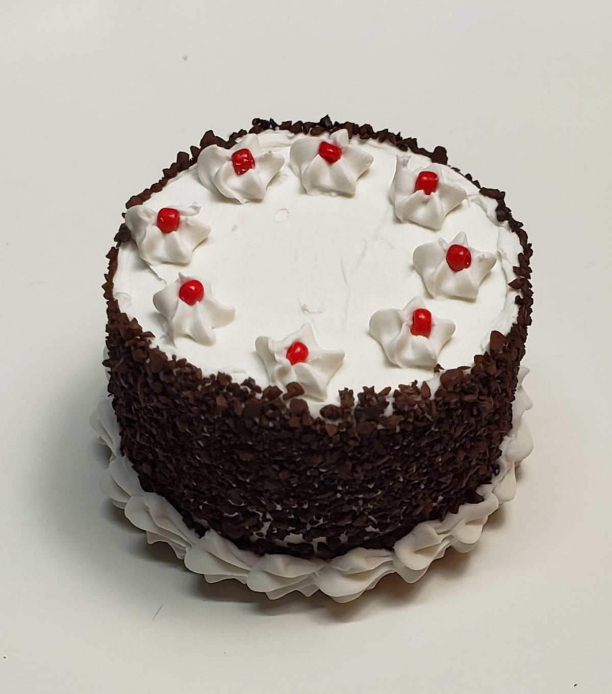 Miniature blackforest cake decorated with cream and cherries on top, perfect for celebrations